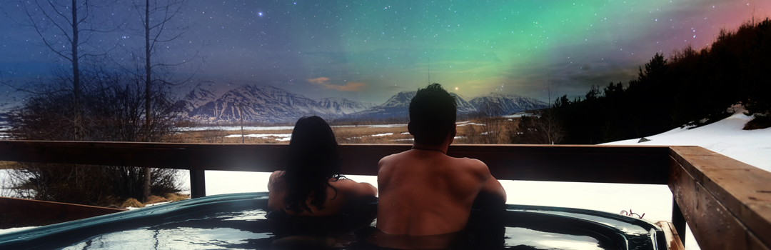 Couple observing Northern Lights from a hot tube in Iceland.