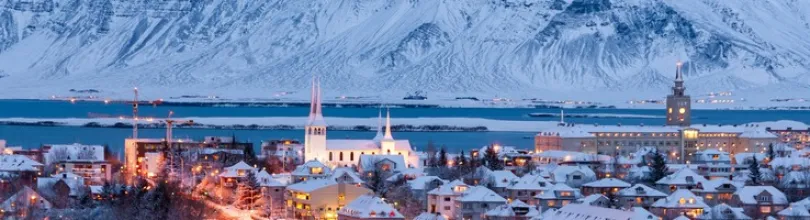 Snow-covered Reykjavík with mountains in the background.