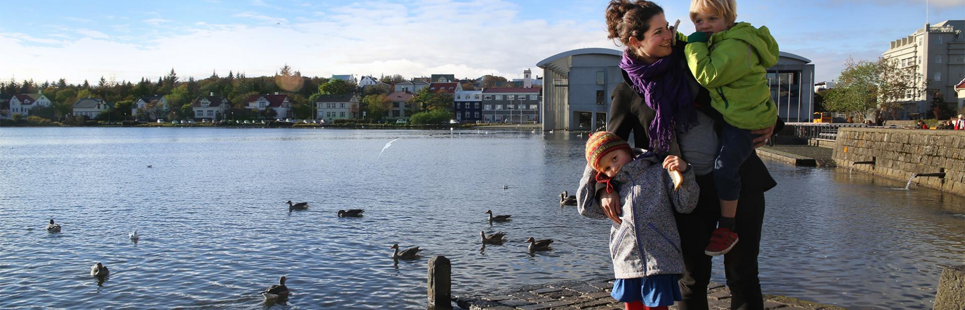 Iceland family holiday with children: woman with two children at the Tjörnin pond, Reykjavik center.
