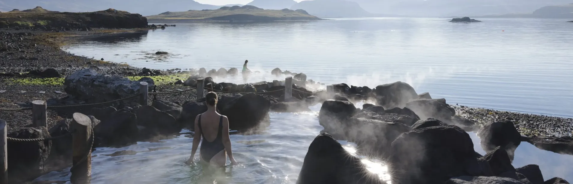 Guest bathing at Hvammsvík Hot Springs by the sea.