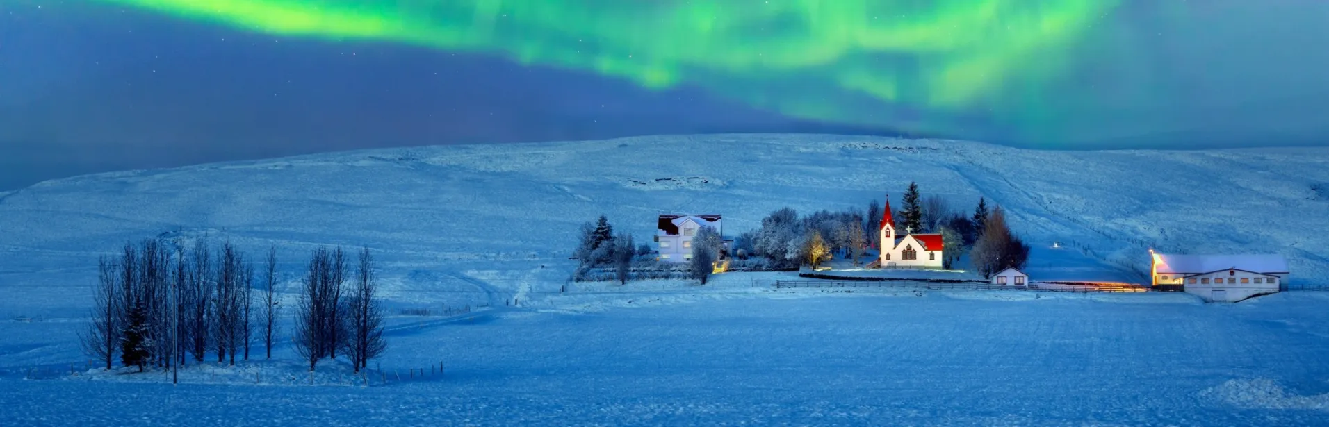 Northern Lights above a snowy landscape in Iceland.