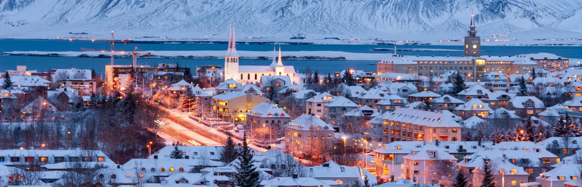 Snow-covered Reykjavík with mountains in the background.