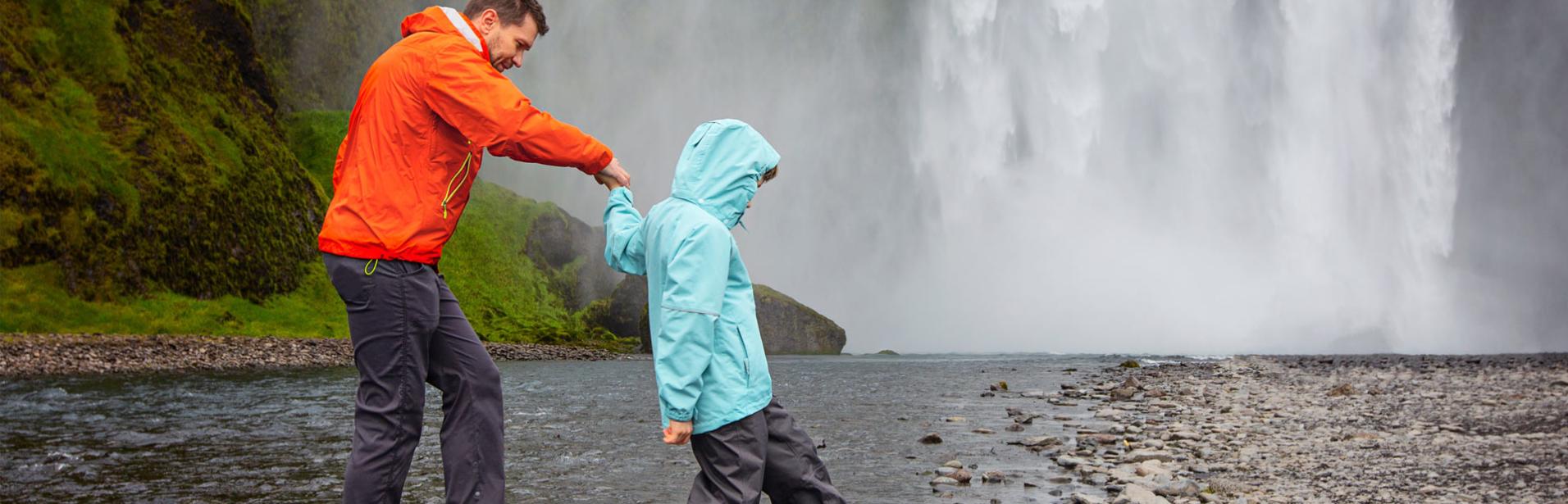 Father and son by waterfall Skogafoss in Iceland.