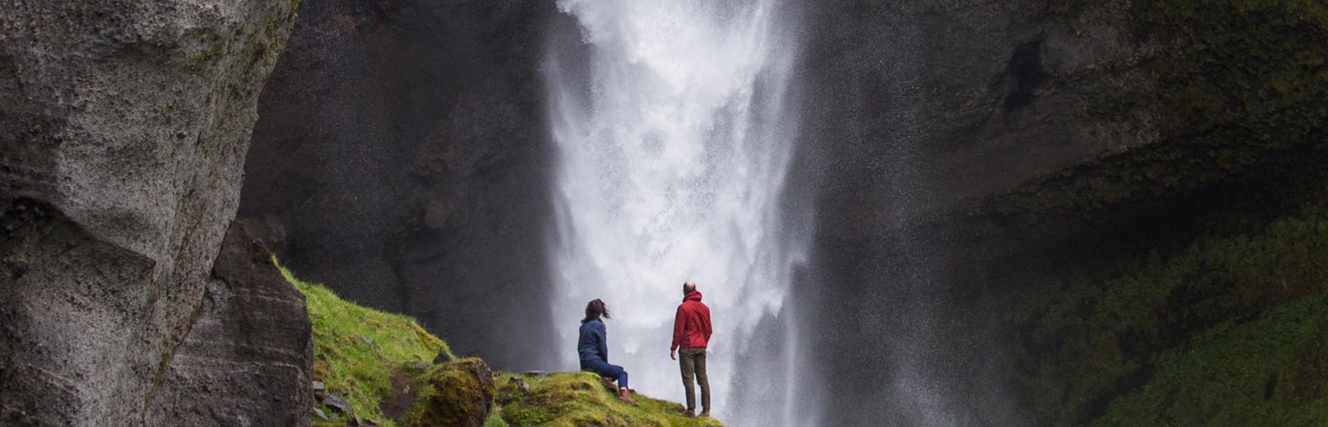 A couple exploring a waterfall in southern Iceland.