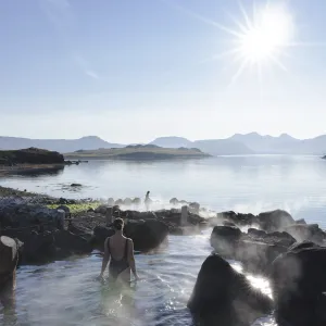 Guest bathing at Hvammsvík Hot Springs by the sea.