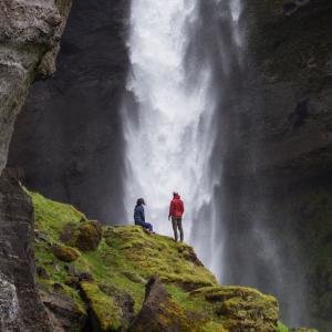 A couple exploring a waterfall in southern Iceland.